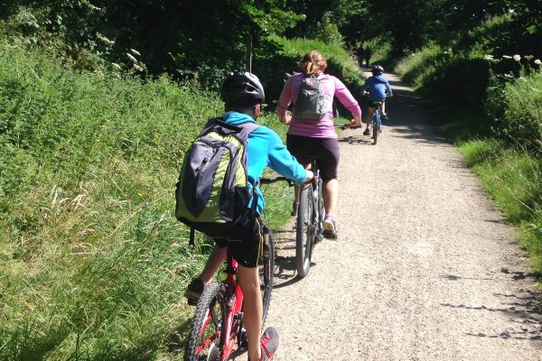 A family on mountain bikes cycling along a gravel path.