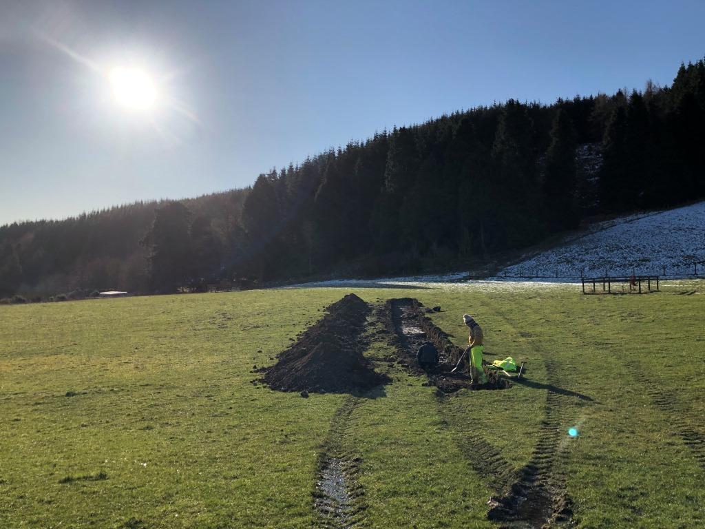 Archaeologist and volunteer in a trench in the sunshine