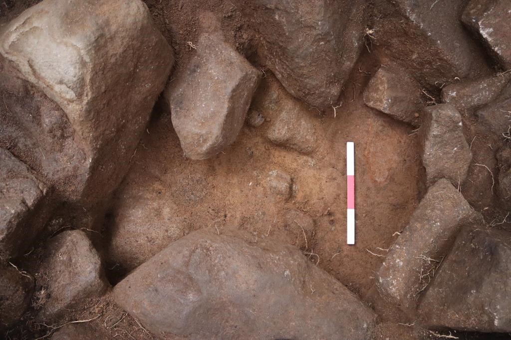 Stones with a pale yellowish deposit beneath them, and a scale bar