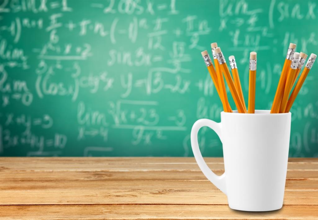 A mug full of pencils in front of a chalkboard