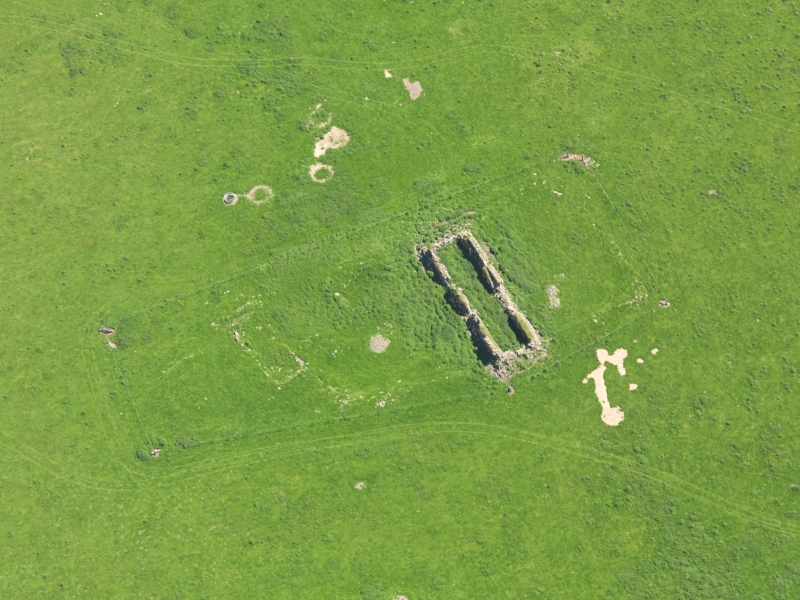 Aerial photo showing ruinous buildings in open grassy pasture