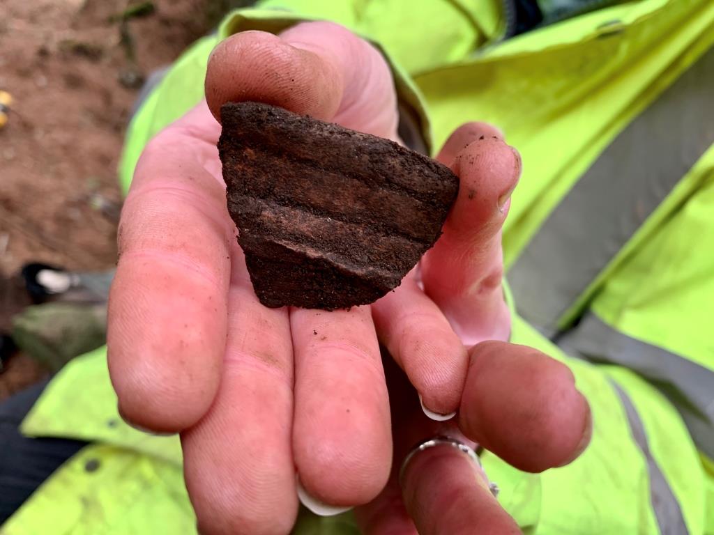 A sherd of rough, unglazed pottery in someone's hand